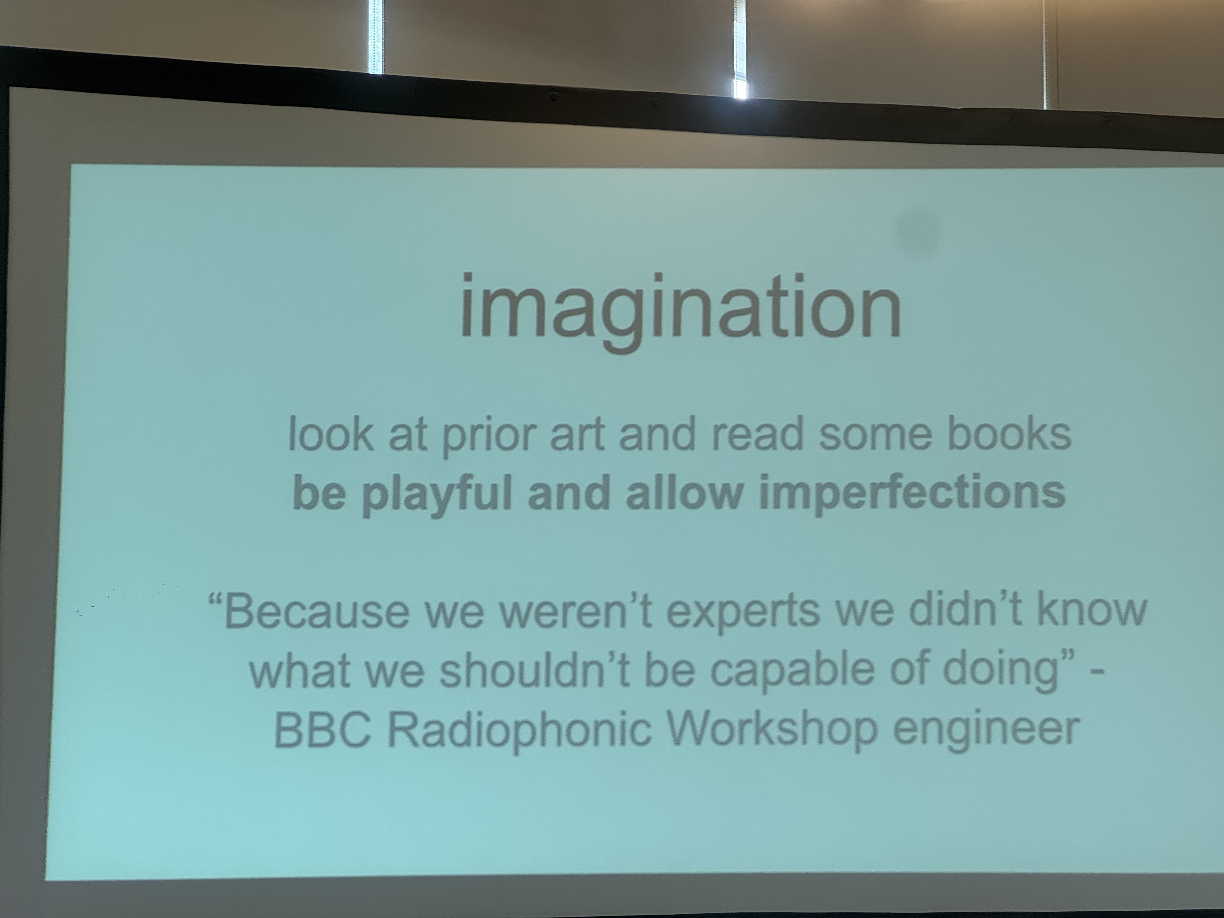 A slide on a projector.  Title: 'imagination'.

look at prior art and read some books
**be playful and allow imperfections**

"Because we weren't experts we didn't know
what we shouldn't be capable of doing" -
BBC Radiophonic Workshop engineer

A speck of dust on an iPhone's 3x-zoom image sensor creates a smudge in the image.