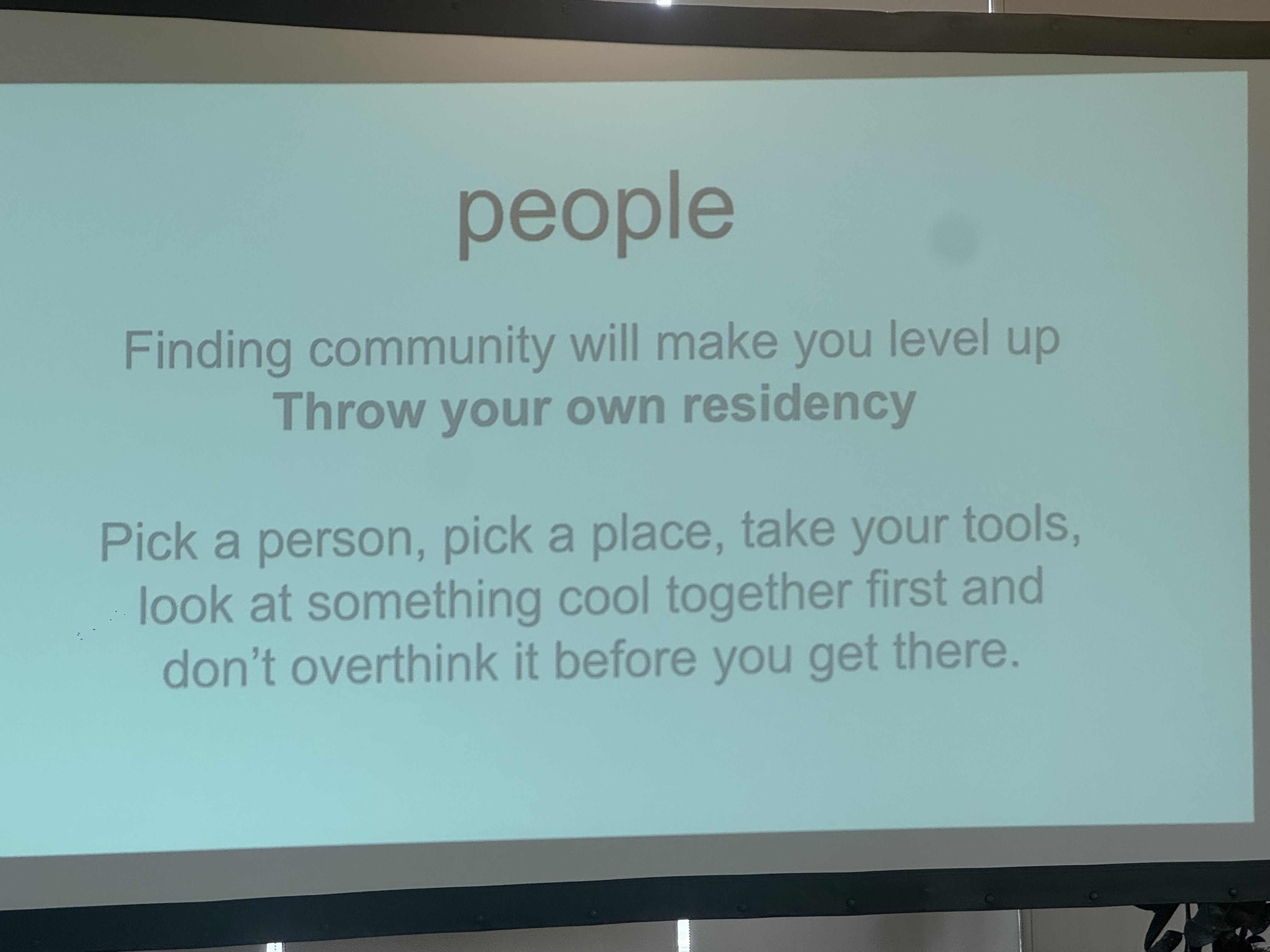 A slide on a projector.  Title: 'people'.

Finding community will make oyu elvel up
**Throw your own residency**

Pick a person, pick a place, take your tools,
look at something cool together first and
don't overthink it before you get there.

A speck of dust on an iPhone's 3x-zoom image sensor creates a smudge in the image.